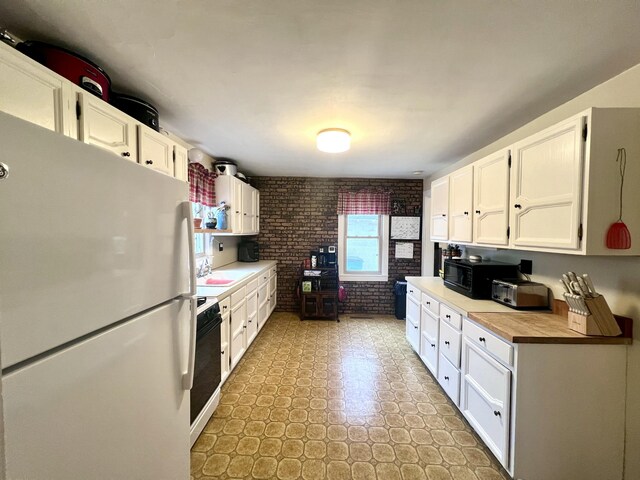 4480 Stanton Blvd, Montague, MI 49437 - kitchen with white cabinets, black microwave, brick wall, range with electric stovetop, and freestanding refrigerator