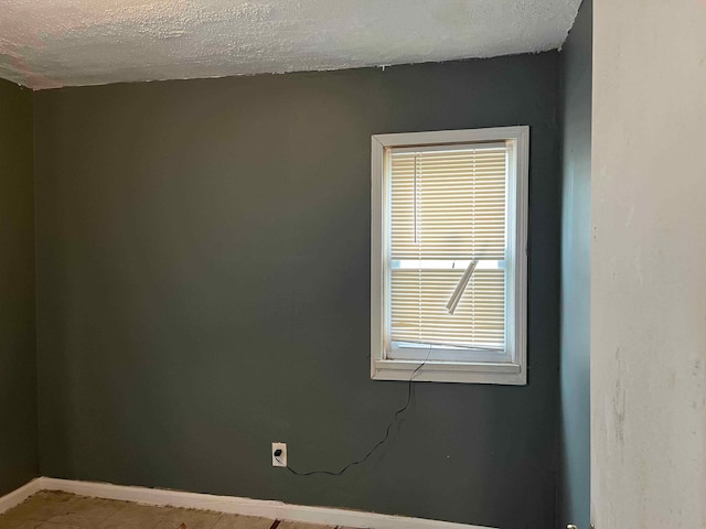 empty room with baseboards and a textured ceiling