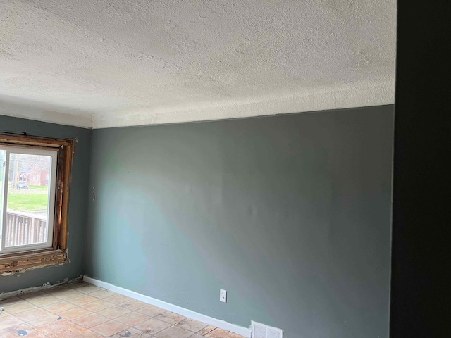 unfurnished room featuring visible vents, a textured ceiling, baseboards, and light tile patterned flooring