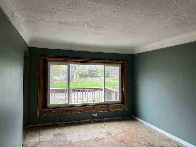 unfurnished room featuring baseboards and a textured ceiling