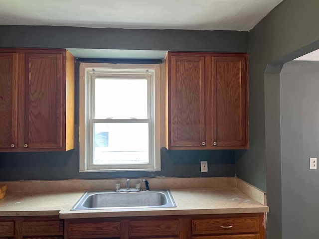 kitchen with a sink, light countertops, and brown cabinetry
