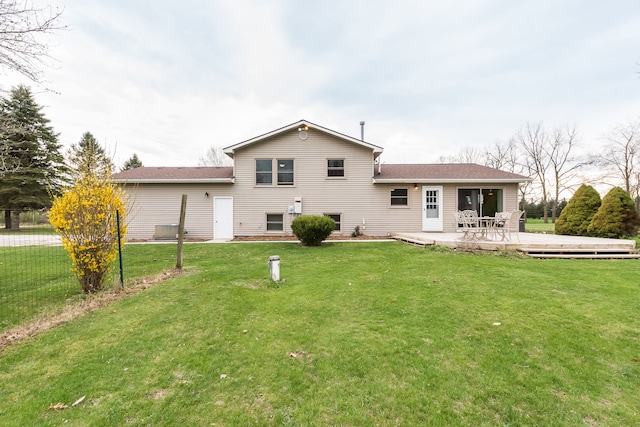 rear view of house with a lawn, fence, and a deck