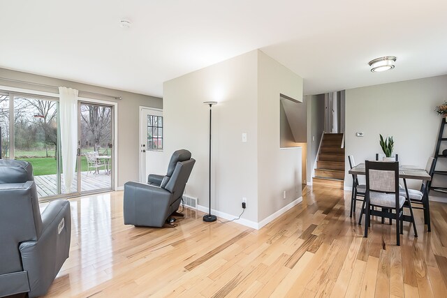 living area with baseboards, visible vents, stairway, and light wood-style floors
