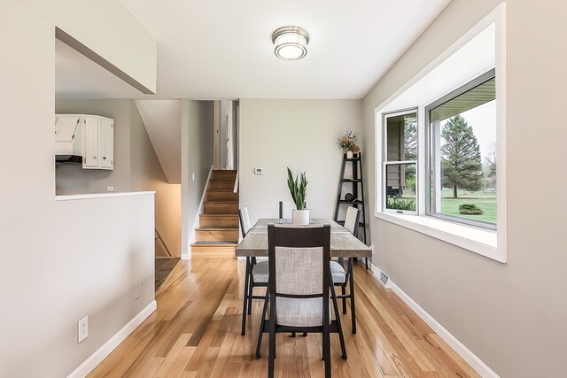dining room with stairs, baseboards, visible vents, and light wood-style flooring
