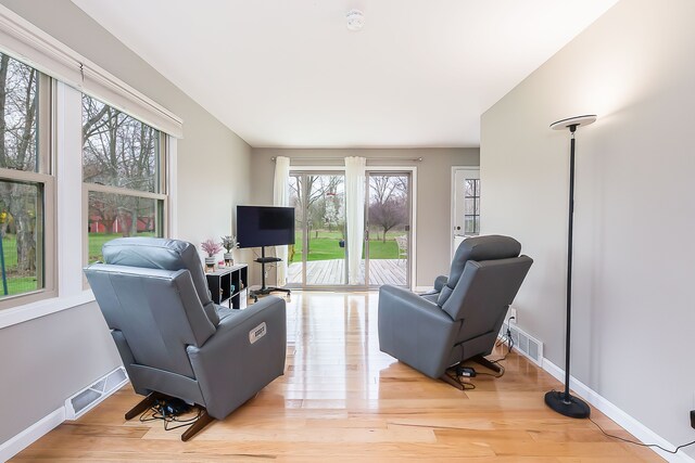 living area with visible vents, baseboards, and wood finished floors