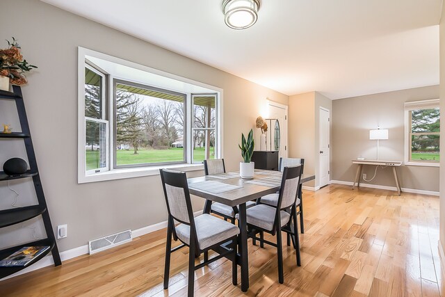 dining area with baseboards, visible vents, and light wood-style flooring