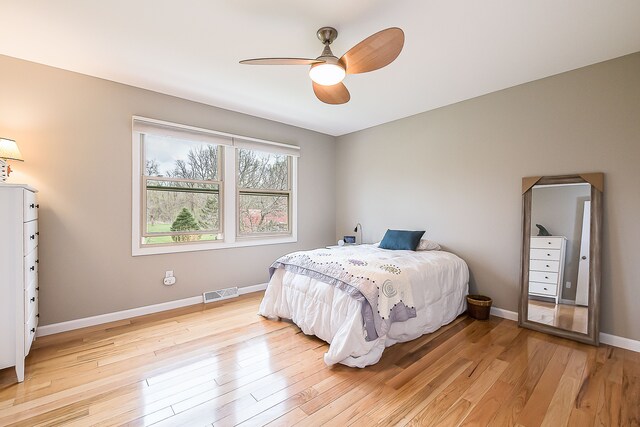 bedroom featuring visible vents, a ceiling fan, light wood finished floors, and baseboards