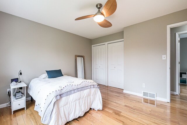 bedroom with baseboards, multiple closets, visible vents, and light wood-style flooring