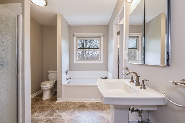 bathroom with tile patterned flooring, toilet, baseboards, a bath, and a stall shower