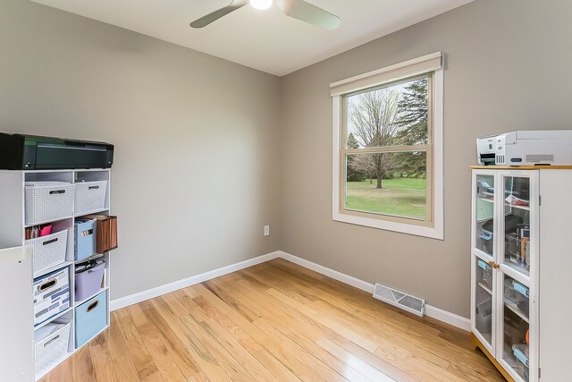 interior space featuring baseboards, a ceiling fan, light wood-type flooring, and visible vents