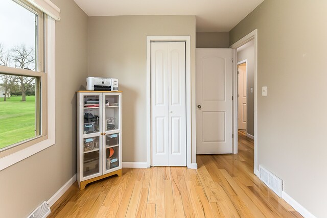 unfurnished bedroom with visible vents, light wood-style flooring, baseboards, and a closet