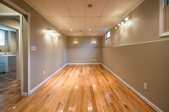 basement with crown molding, light wood-style flooring, washer / dryer, and baseboards