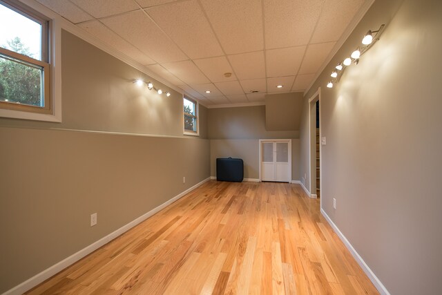 below grade area featuring baseboards, ornamental molding, wood finished floors, and a wealth of natural light