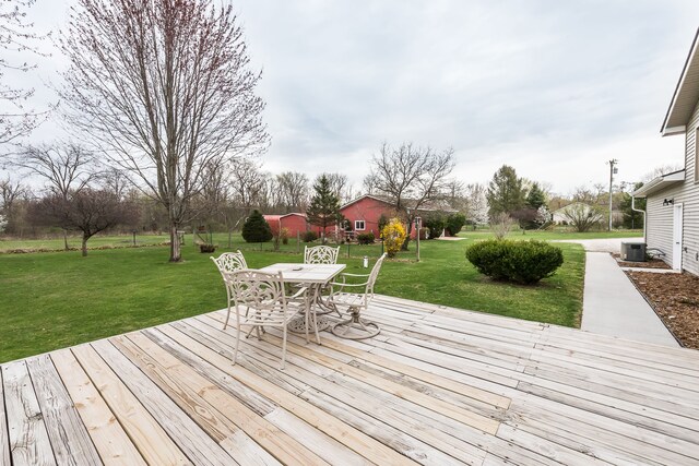 wooden terrace featuring a lawn, cooling unit, and outdoor dining space
