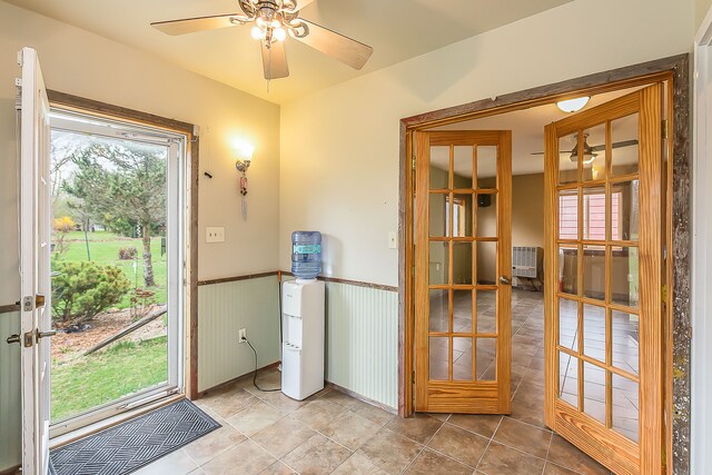 entryway with french doors, tile patterned flooring, ceiling fan, and wainscoting