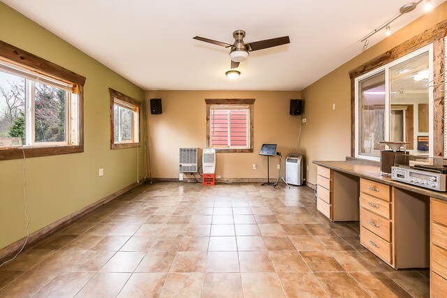 interior space featuring baseboards, a ceiling fan, and light tile patterned floors