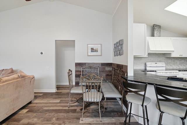 dining area with baseboards, vaulted ceiling, and wood finished floors