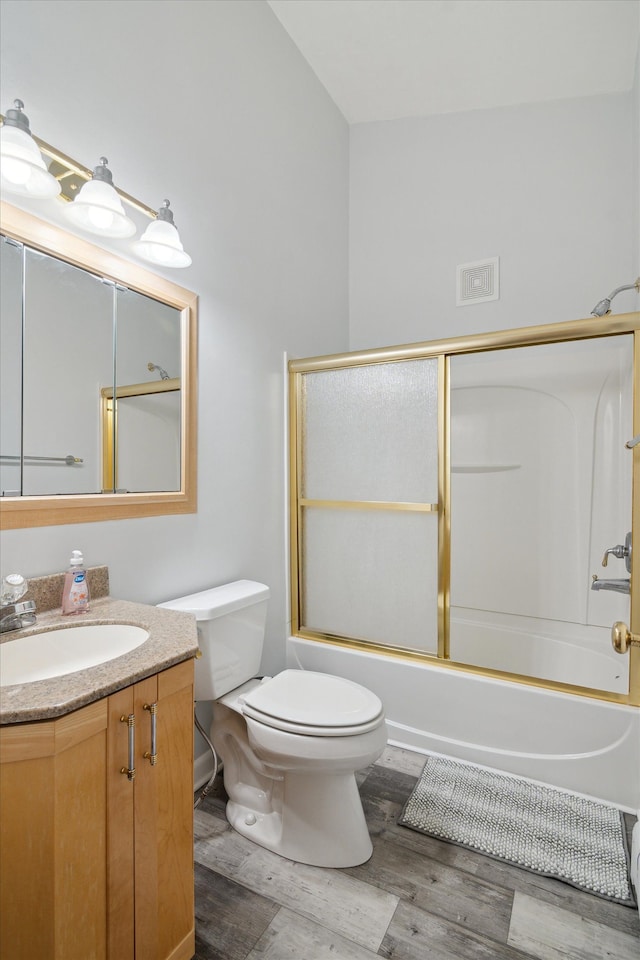 full bathroom featuring toilet, vanity, wood finished floors, enclosed tub / shower combo, and visible vents