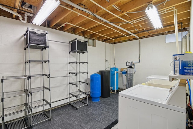 clothes washing area with concrete block wall, independent washer and dryer, and laundry area