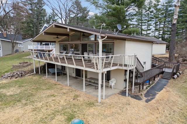 back of property with stairway, a ceiling fan, a deck, a patio, and a yard