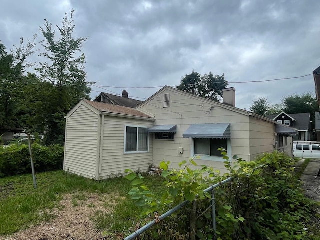 view of front facade with a chimney and fence