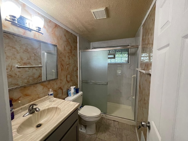 bathroom featuring a stall shower, toilet, vanity, a textured ceiling, and visible vents