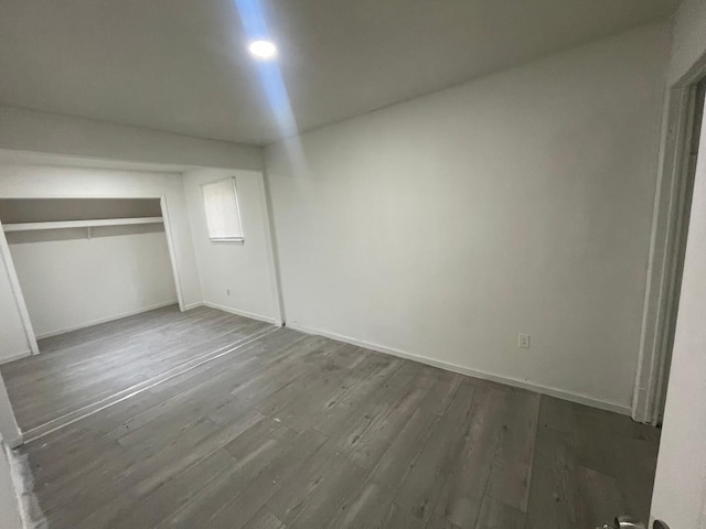 unfurnished bedroom featuring baseboards, dark wood-style floors, and a closet