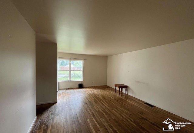 unfurnished room featuring wood finished floors, baseboards, and visible vents