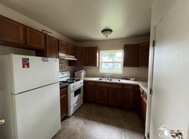 kitchen featuring light countertops, a sink, brown cabinets, under cabinet range hood, and white appliances