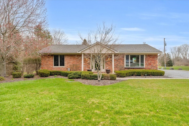 single story home featuring a front lawn, a shingled roof, and brick siding