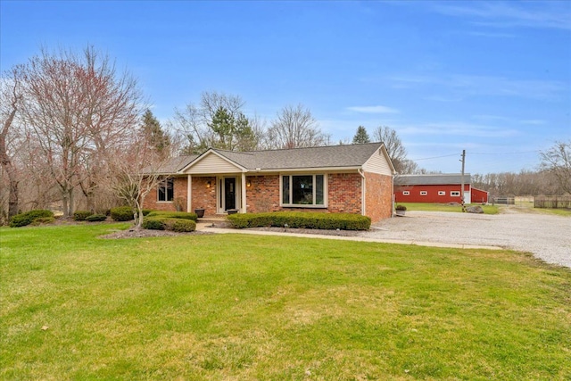 ranch-style home with a front lawn, driveway, roof with shingles, and brick siding