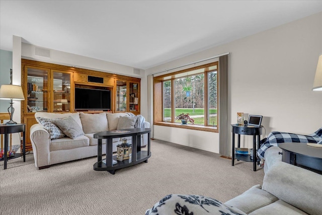 living area featuring baseboards, visible vents, and light carpet