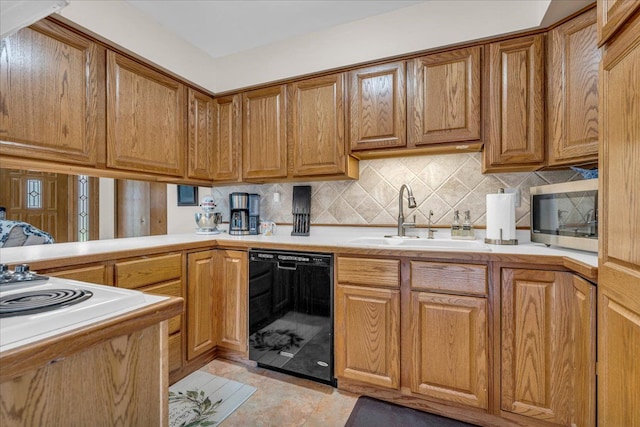 kitchen featuring stainless steel microwave, dishwasher, light countertops, and a sink