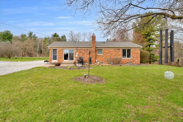 view of front facade featuring a front lawn, a chimney, gravel driveway, and brick siding