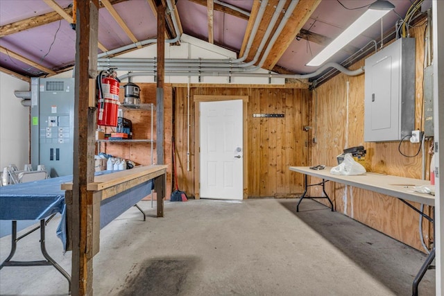below grade area featuring wooden walls, a workshop area, and electric panel