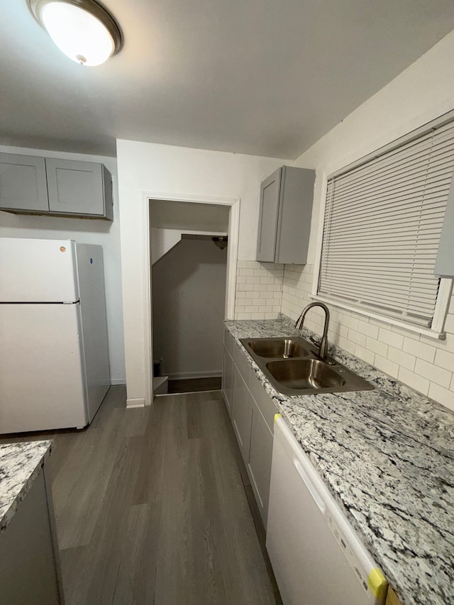 kitchen with dark wood-style floors, a sink, gray cabinetry, and white appliances