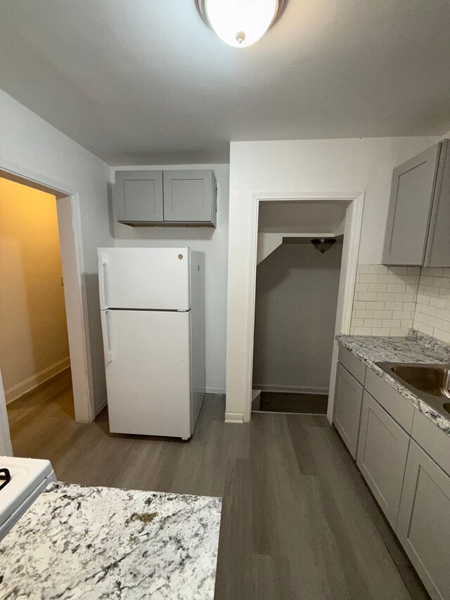 kitchen featuring baseboards, freestanding refrigerator, gray cabinetry, wood finished floors, and decorative backsplash