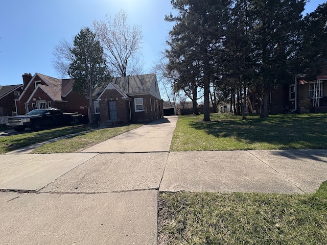 view of front of property with a garage, a front yard, brick siding, and driveway