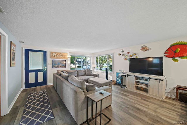 living area with visible vents, baseboards, a textured ceiling, and wood finished floors