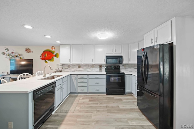 kitchen featuring a textured ceiling, a sink, light countertops, black appliances, and a peninsula