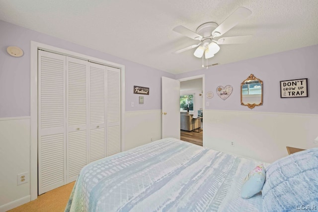 carpeted bedroom featuring ceiling fan, a closet, and a textured ceiling