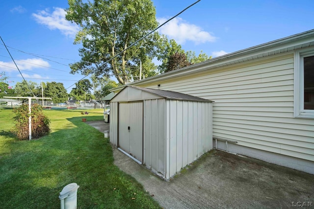 view of side of home with a storage unit, a lawn, and an outbuilding