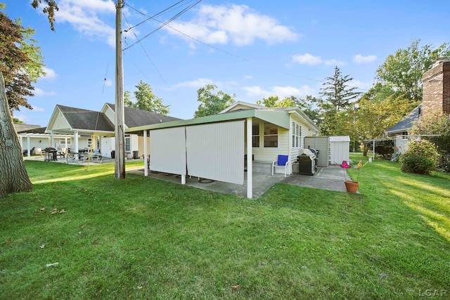 back of property featuring a yard, an outdoor structure, a patio area, and a shed