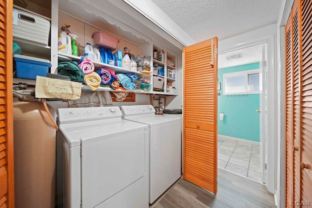 clothes washing area with laundry area, a textured ceiling, independent washer and dryer, and visible vents