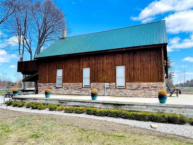 view of side of home with stone siding and metal roof