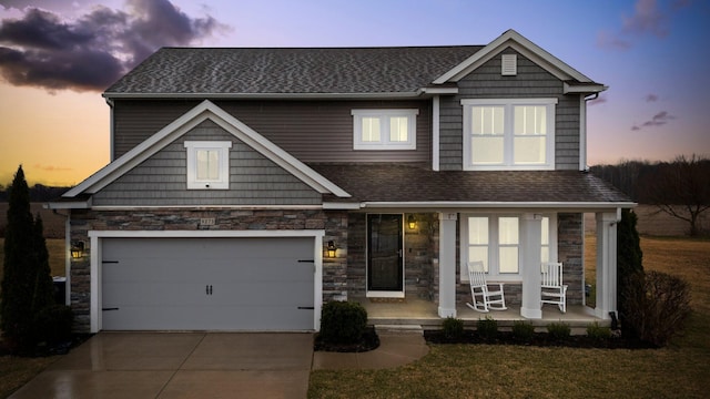 view of front of home with concrete driveway, an attached garage, stone siding, covered porch, and a shingled roof