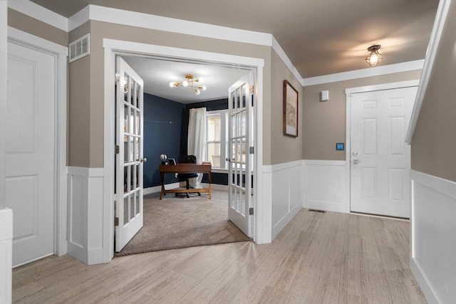 entrance foyer featuring french doors, wainscoting, light wood finished floors, and visible vents