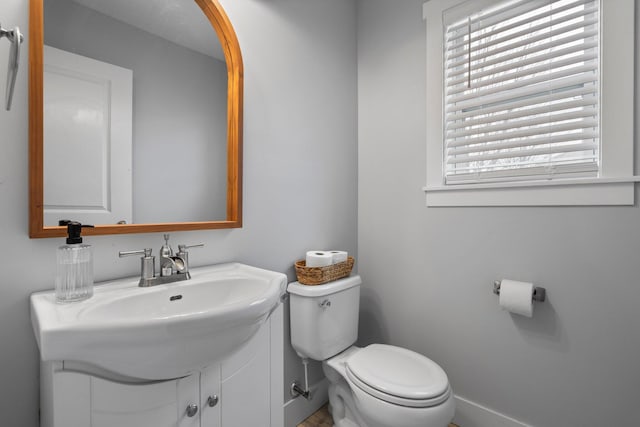 bathroom with baseboards, toilet, and vanity