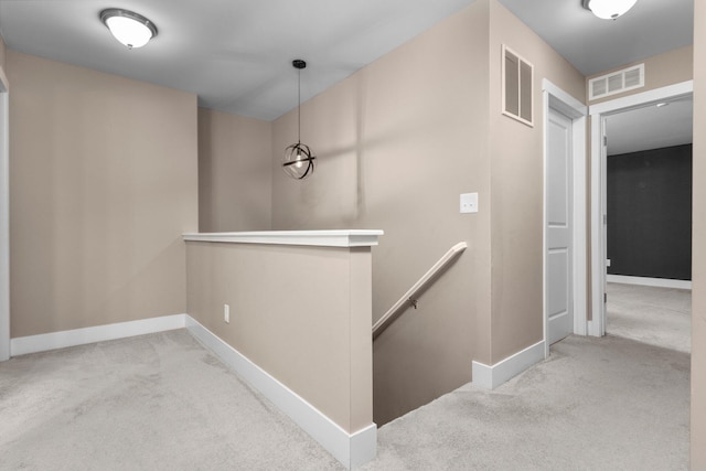 corridor featuring baseboards, visible vents, an upstairs landing, and carpet