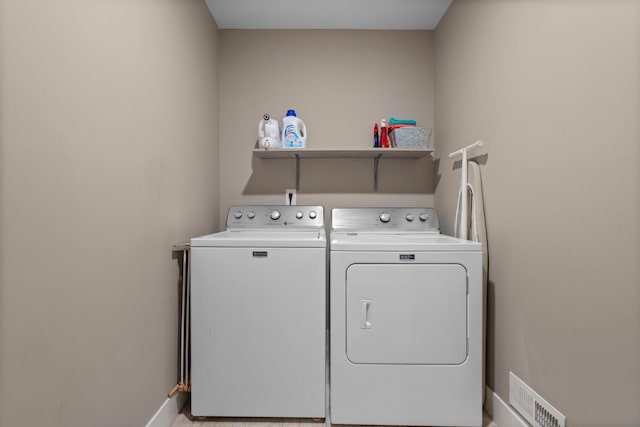 clothes washing area featuring washing machine and dryer, baseboards, laundry area, and visible vents